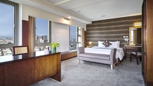 Habitación de hotel con una cama grande, un escritorio, una silla, un espejo y vistas a la ciudad.