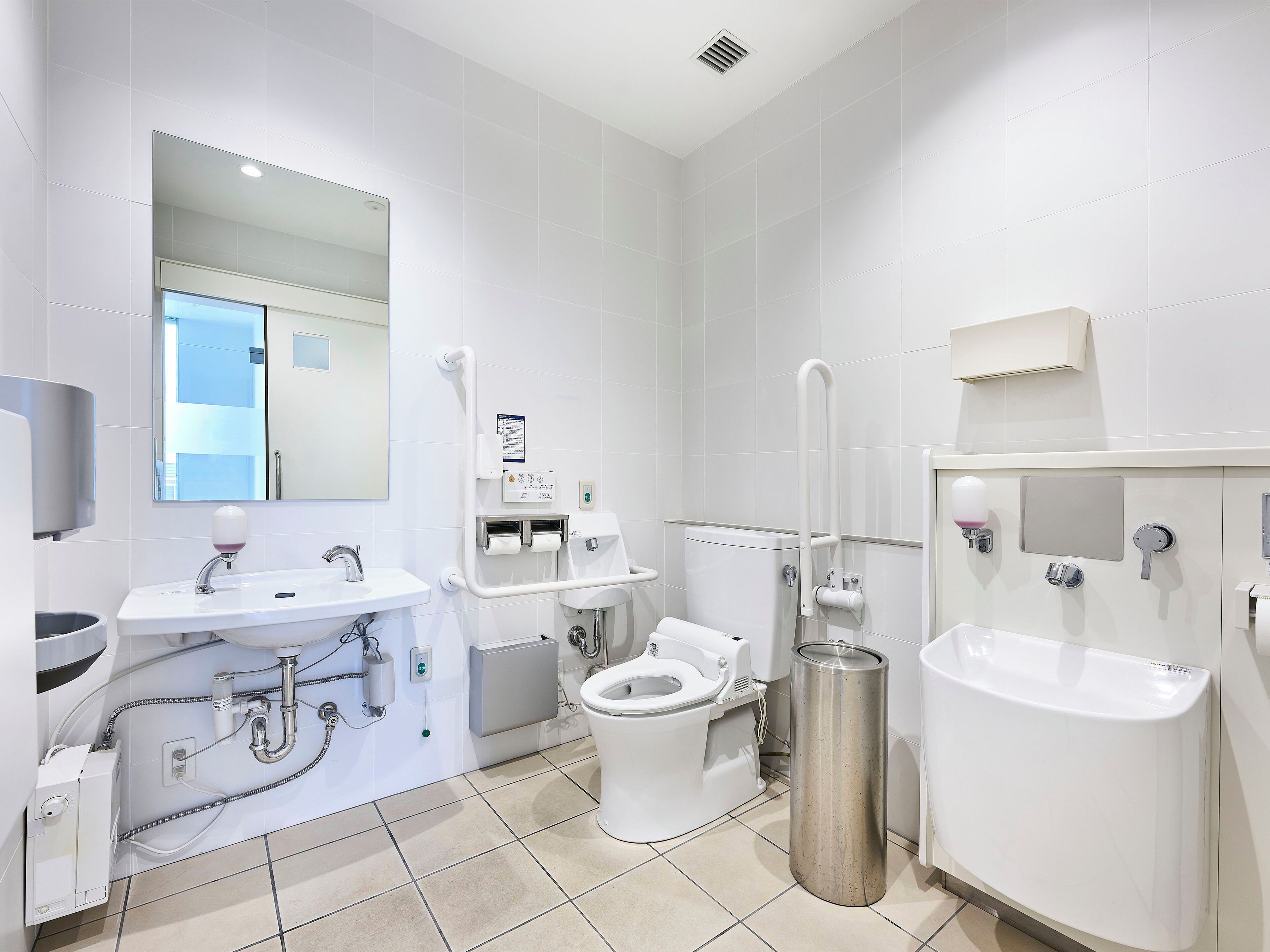 A modern bathroom with a toilet, bidet, sink, and bidet shower.