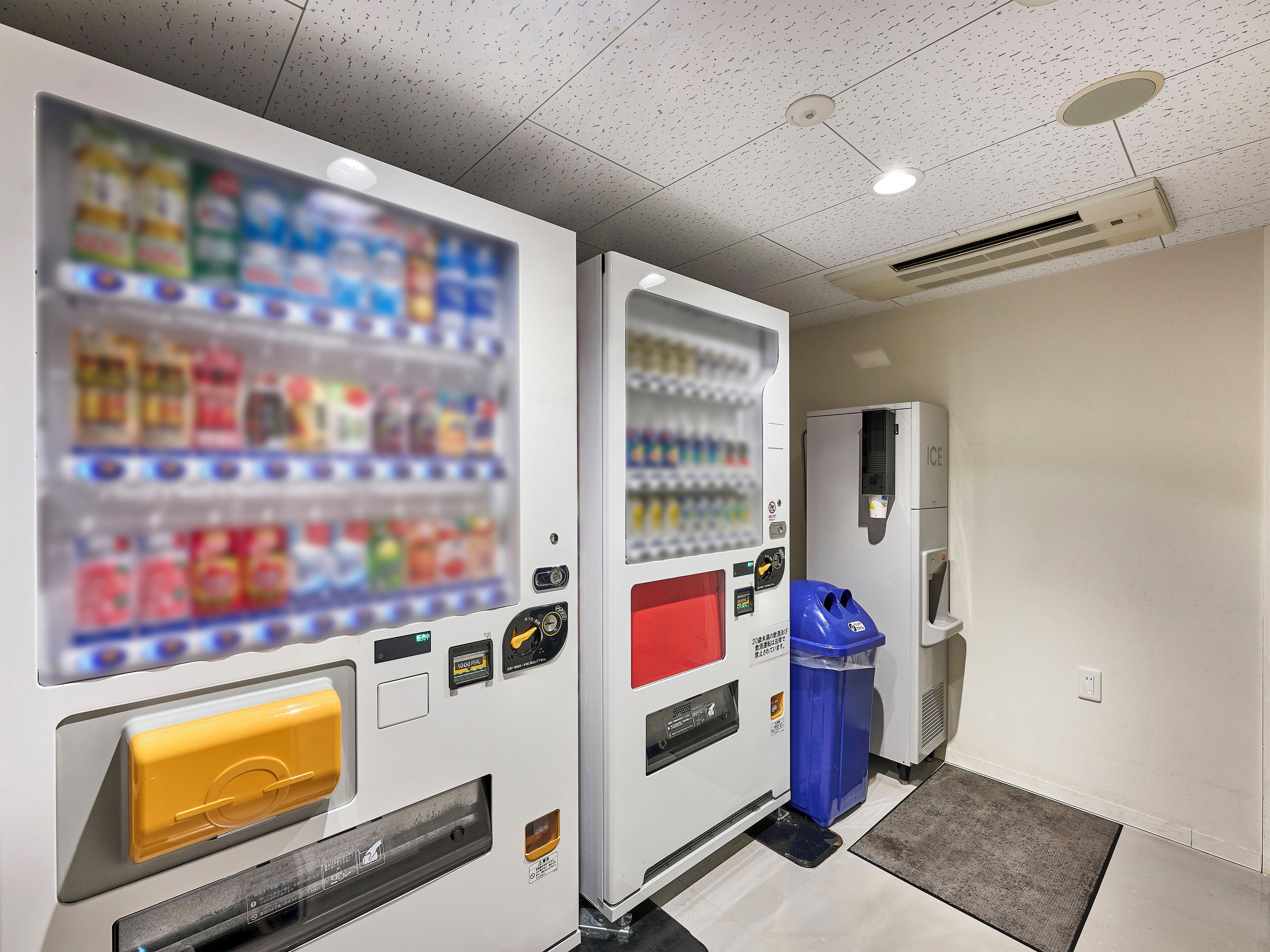 A vending machine area with a beverage dispenser and a trash bin.