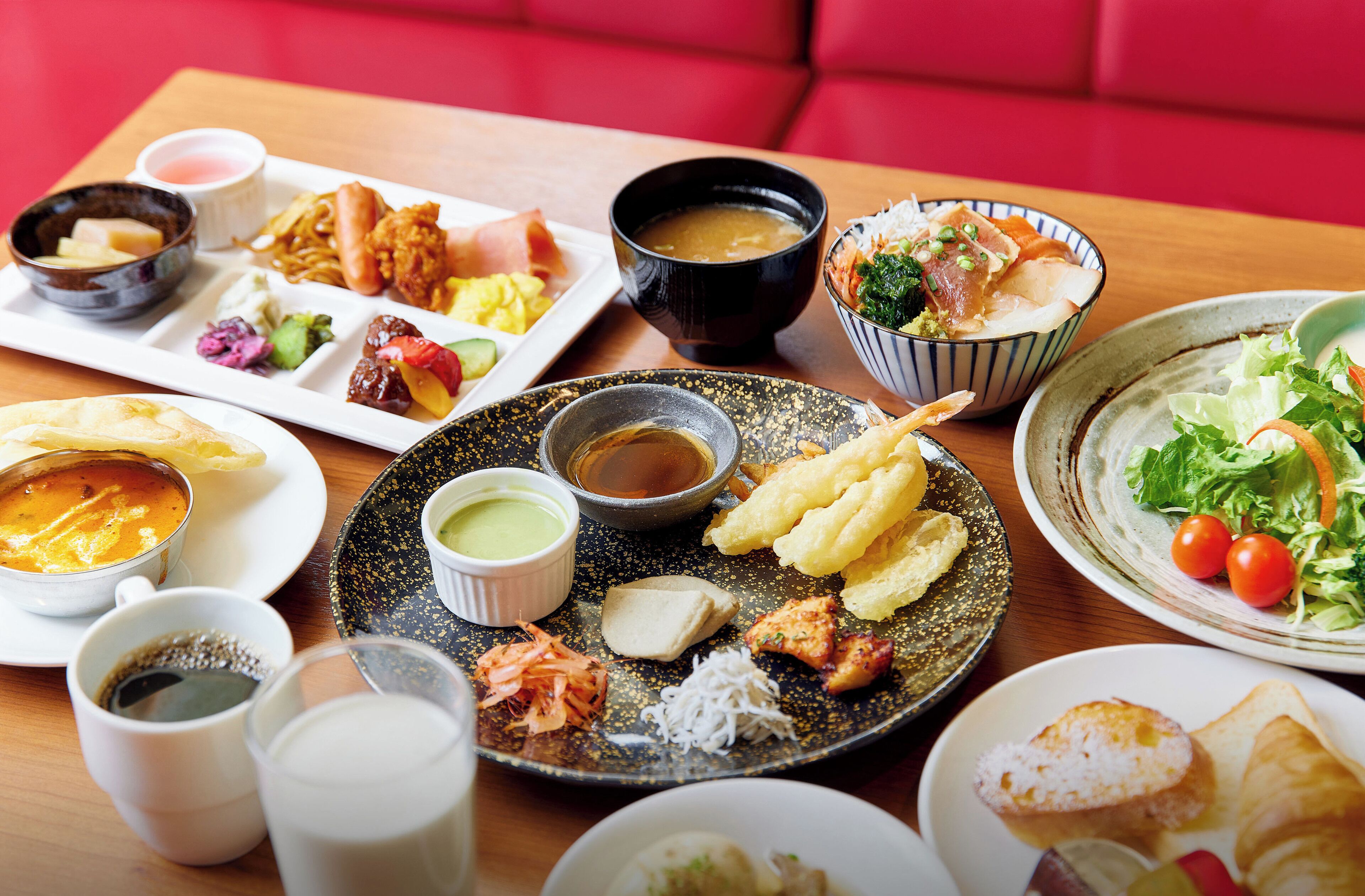A table with various dishes including sushi, a bowl of soup, and a plate of vegetables.