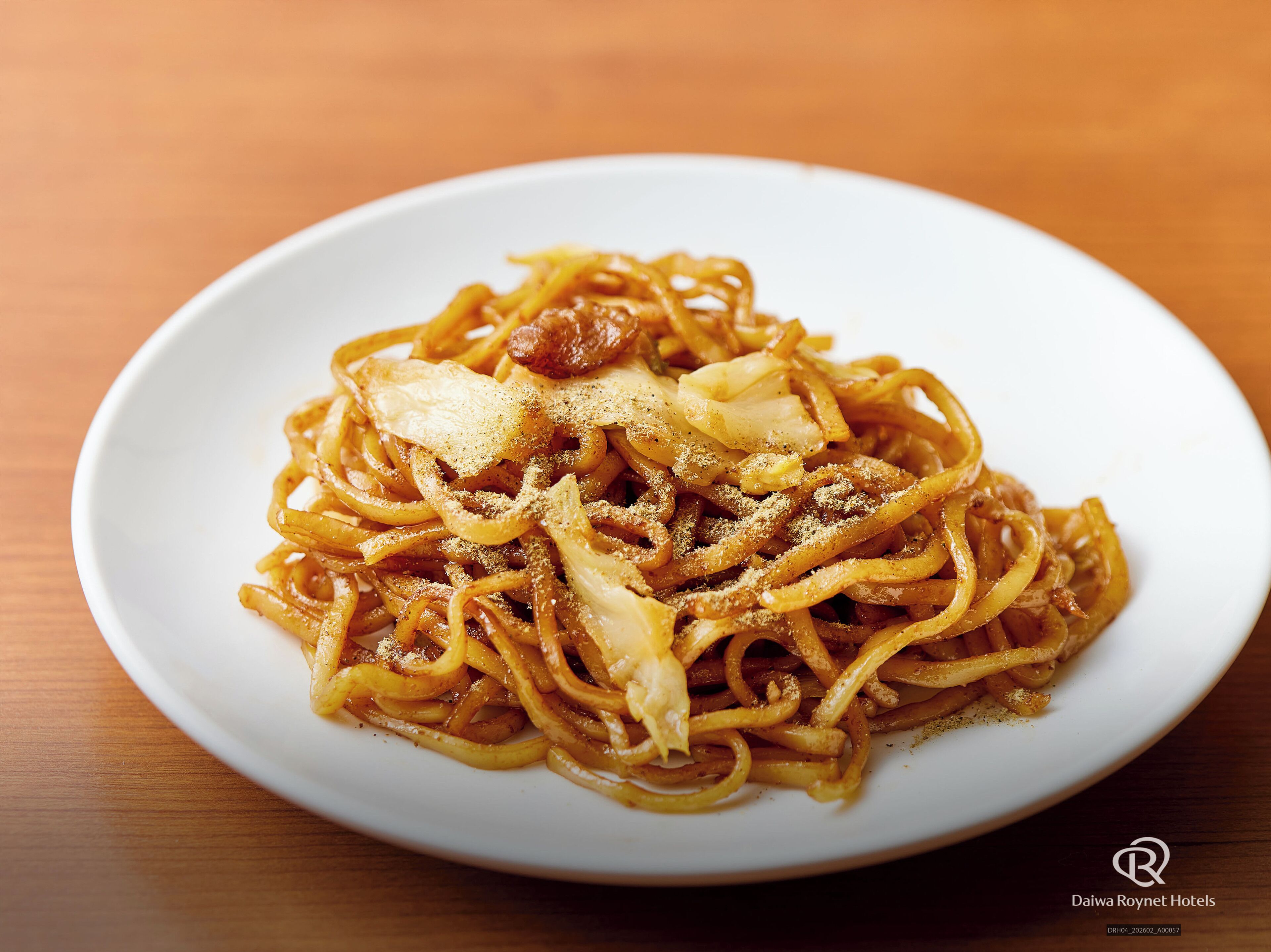 A plate of spaghetti with a tomato-based sauce, topped with grated cheese and herbs, served on a white plate.