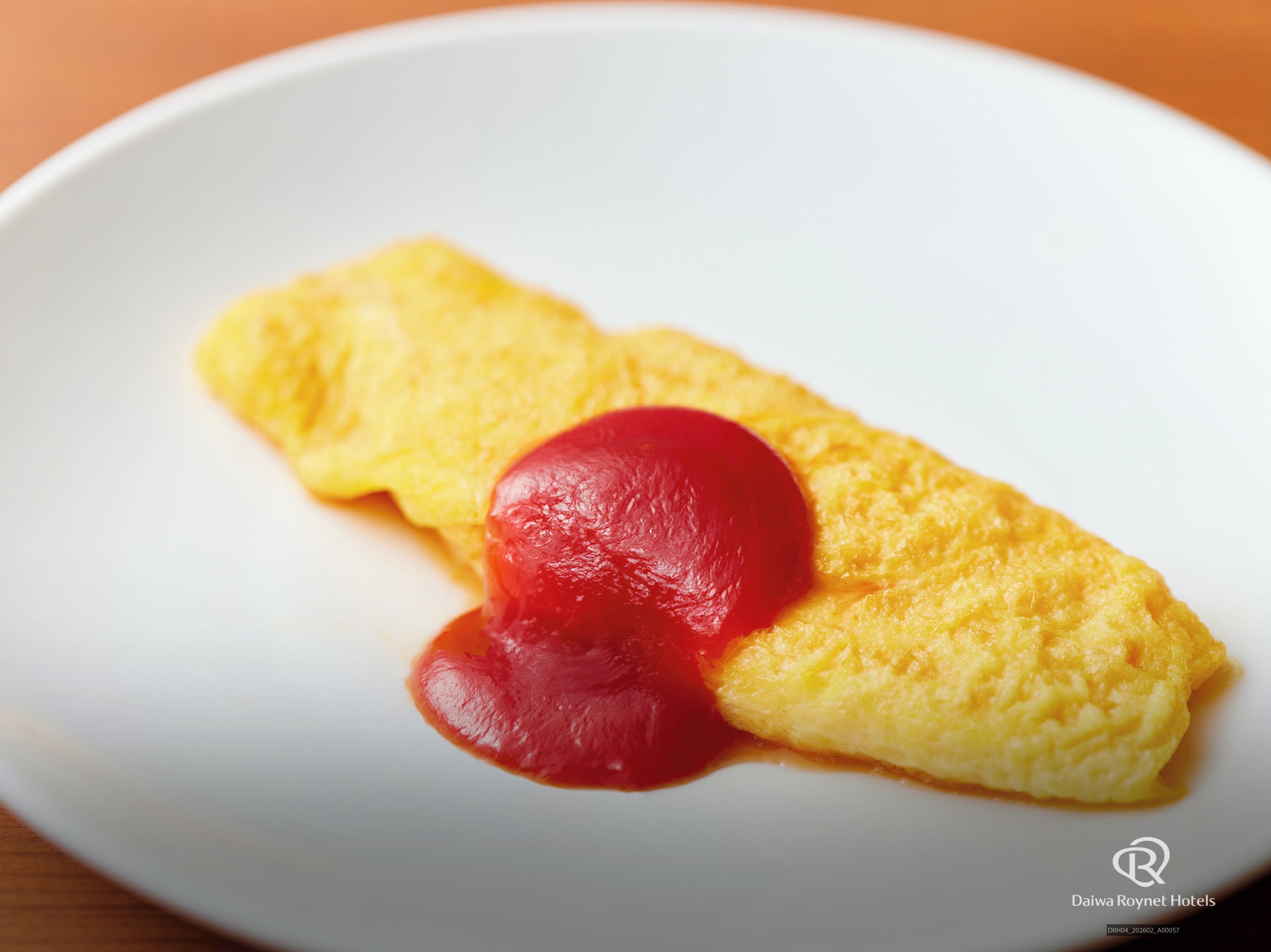 Um prato com um omelete dobrado e uma porção de molho vermelho.