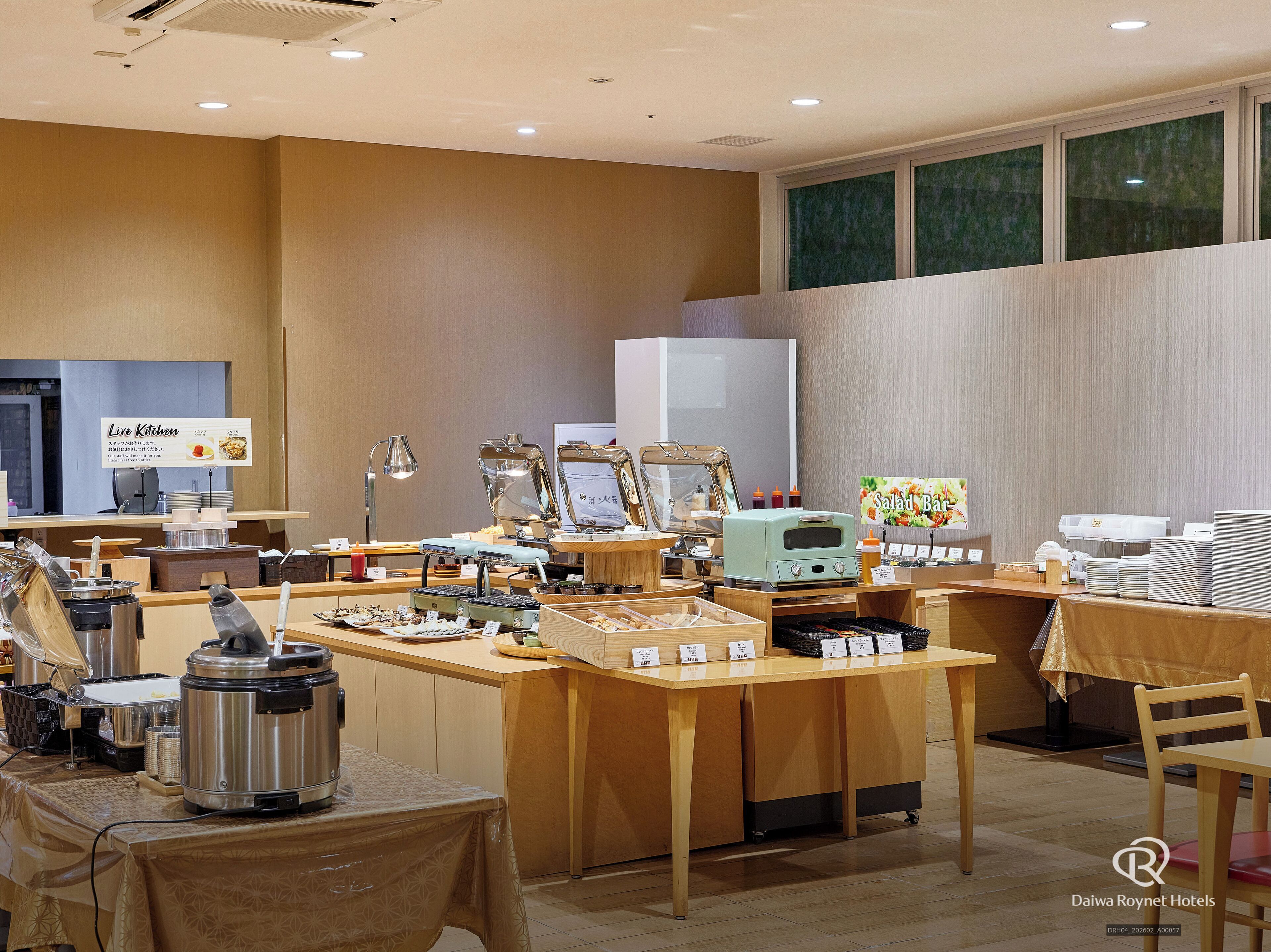 A buffet setup with various food stations, a coffee machine, and a salad bar sign.