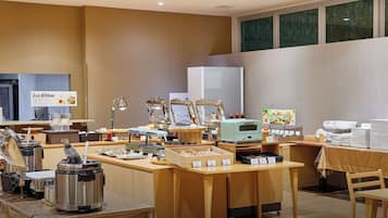 A buffet setup with various food stations, a coffee machine, and a salad bar sign.
