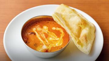 A bowl of soup with a folded crepe on a white plate.
