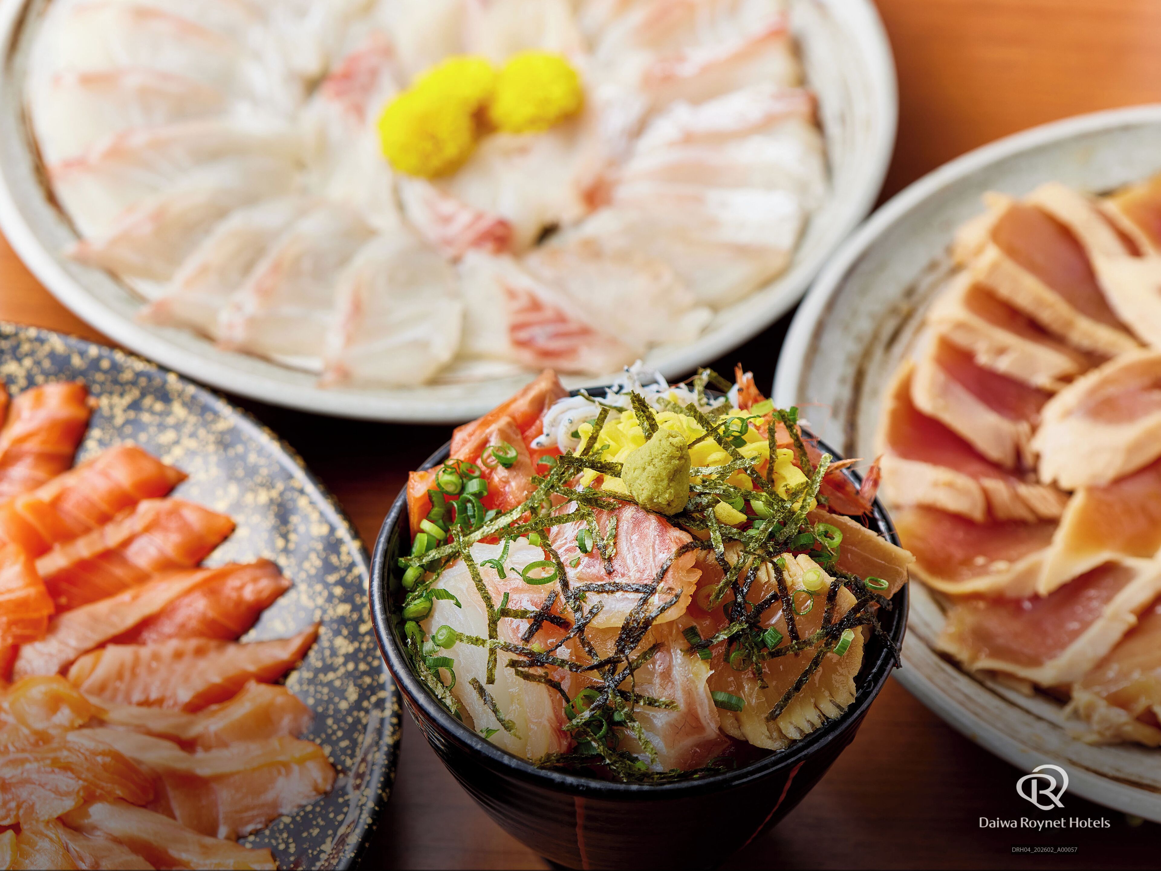 A bowl of sashimi with green onions and seaweed garnish.
