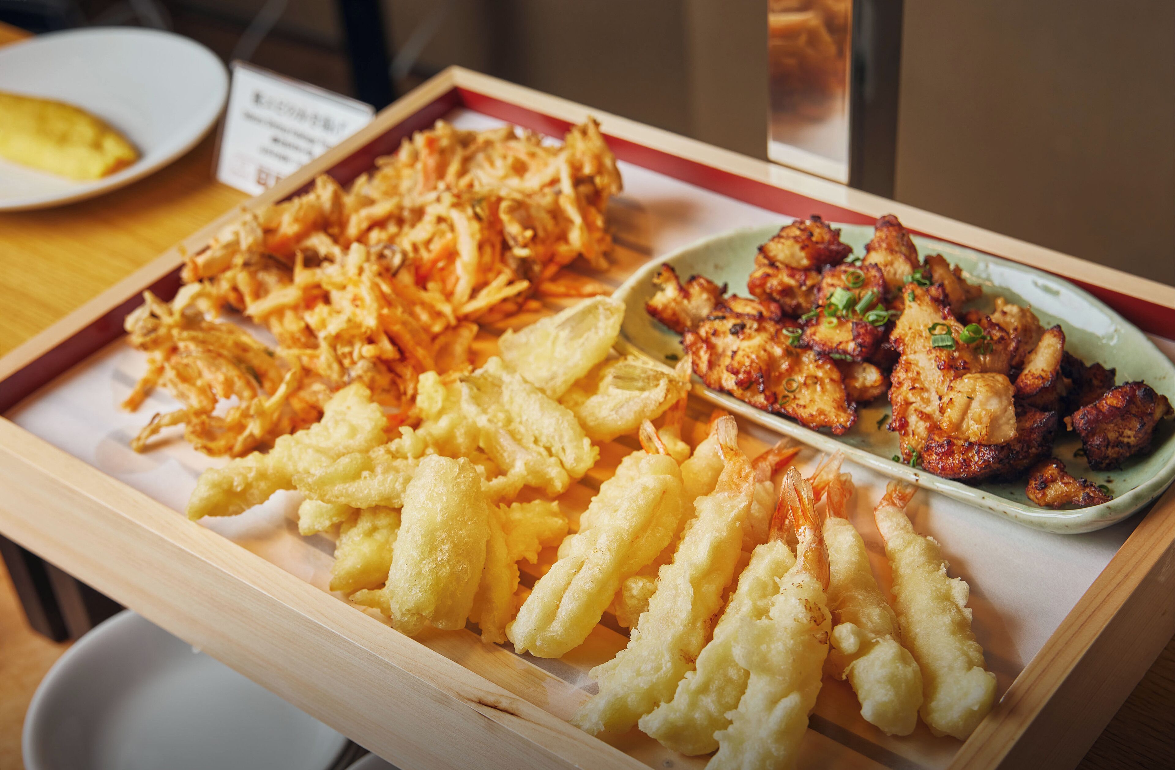 Uma travessa de tempura com camarões e legumes.