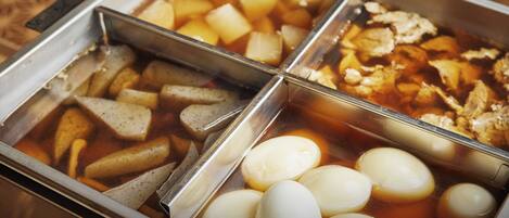 Un bufé con diversas opciones de comida, incluyendo patatas, carne y huevos cocidos.