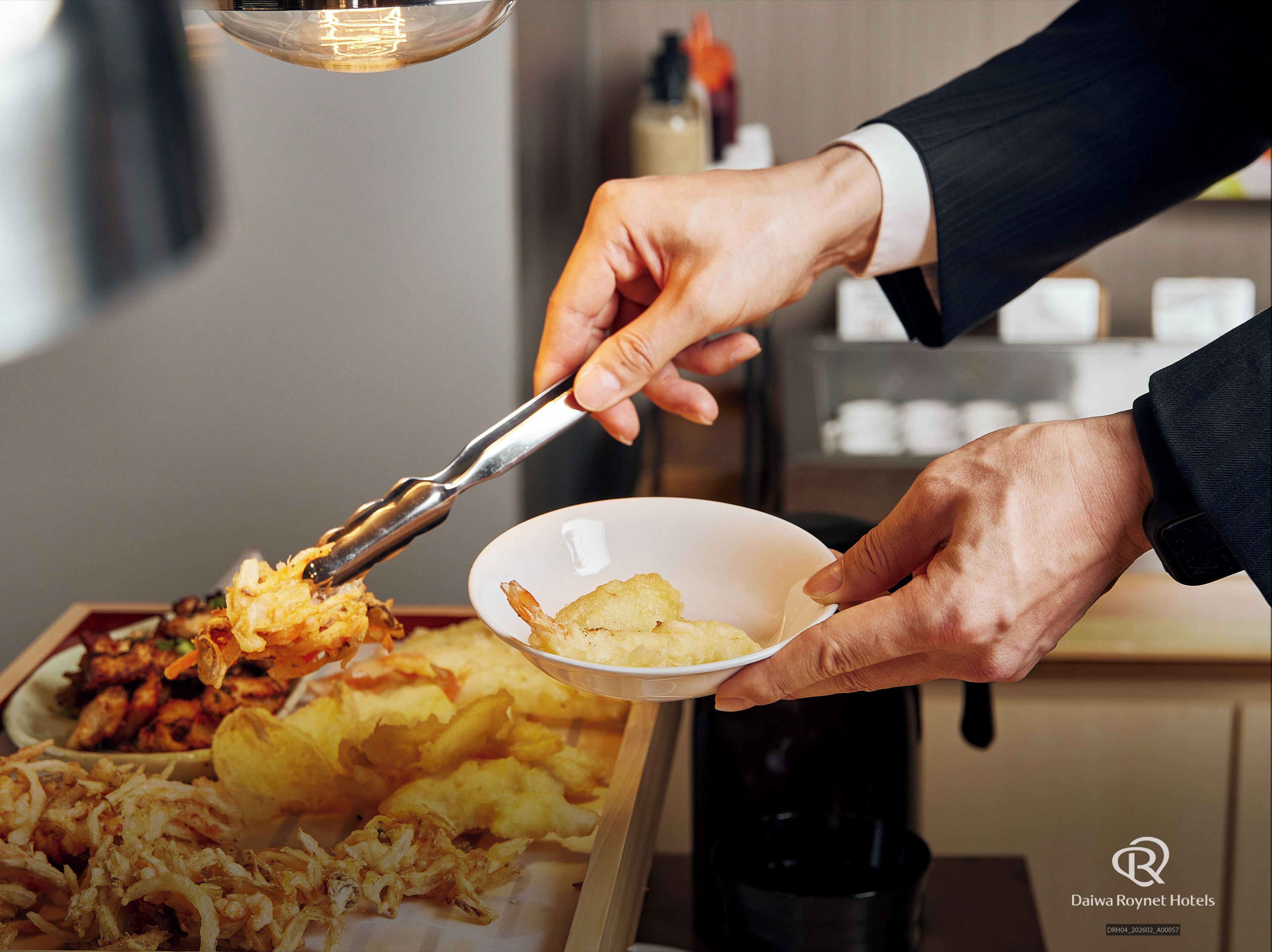 A person serving food from a tray to a bowl.