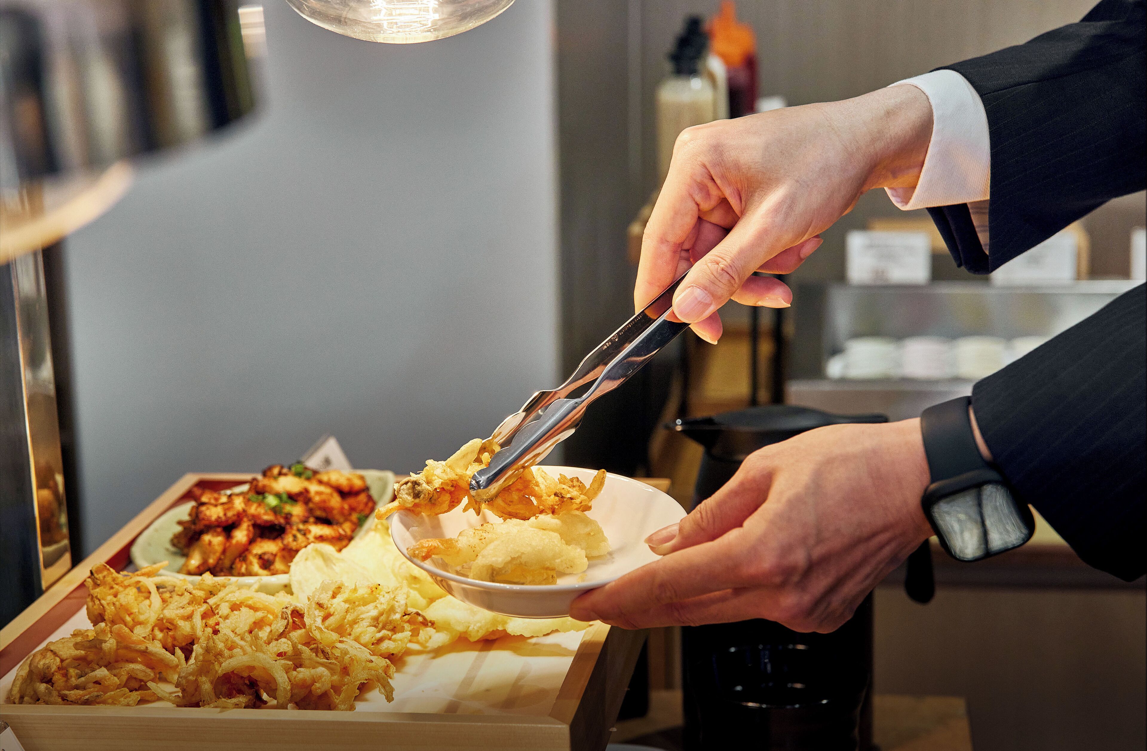 A person serving food from a tray to another person.