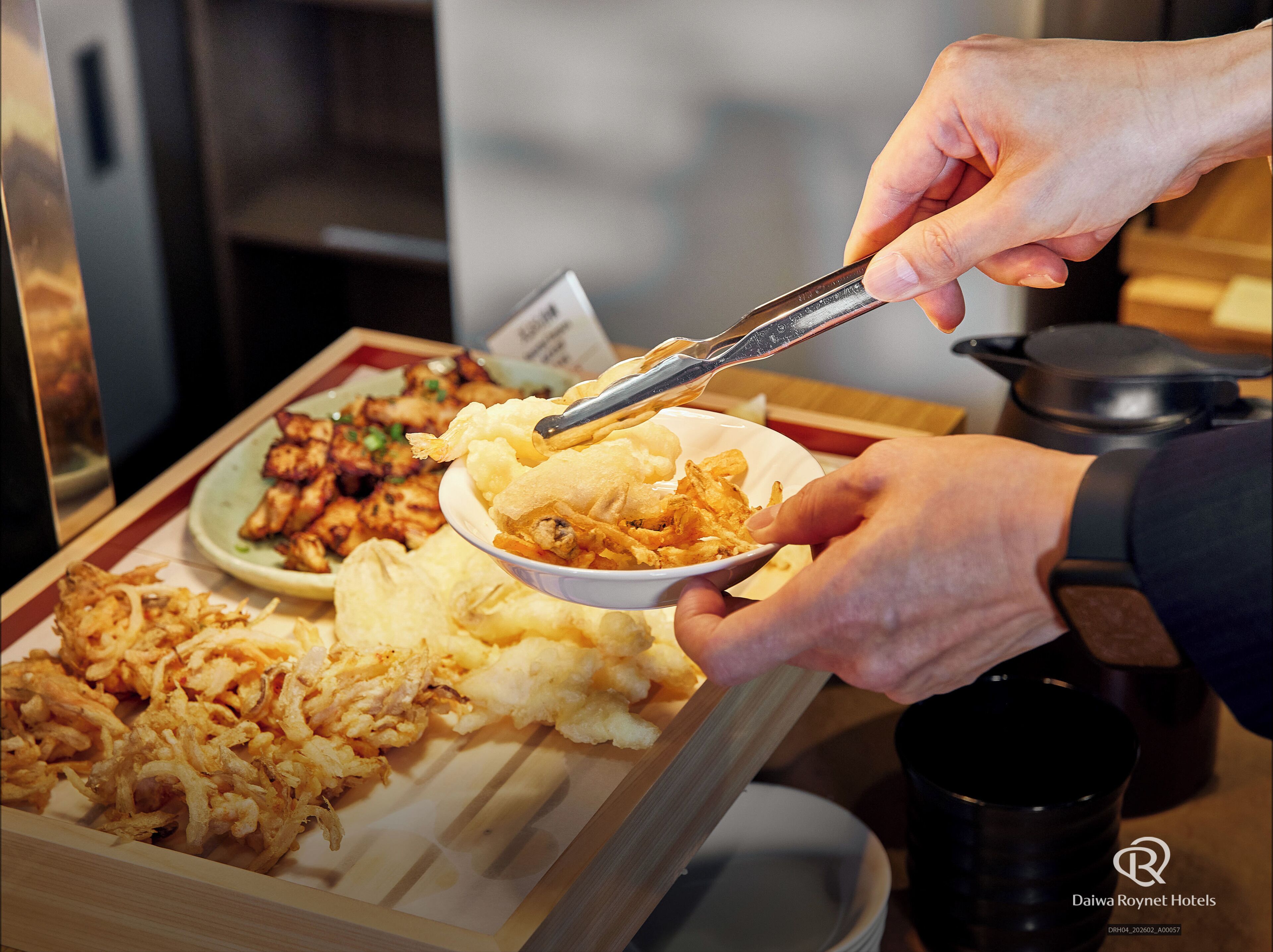 A person serving food from a bowl using tongs.