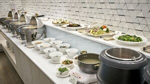 En buffetopstilling med forskellige retter og en stor gryde på komfuret.