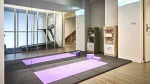 Et moderne fitnesscenter med træningsudstyr, yogamåtter og et løbebånd.