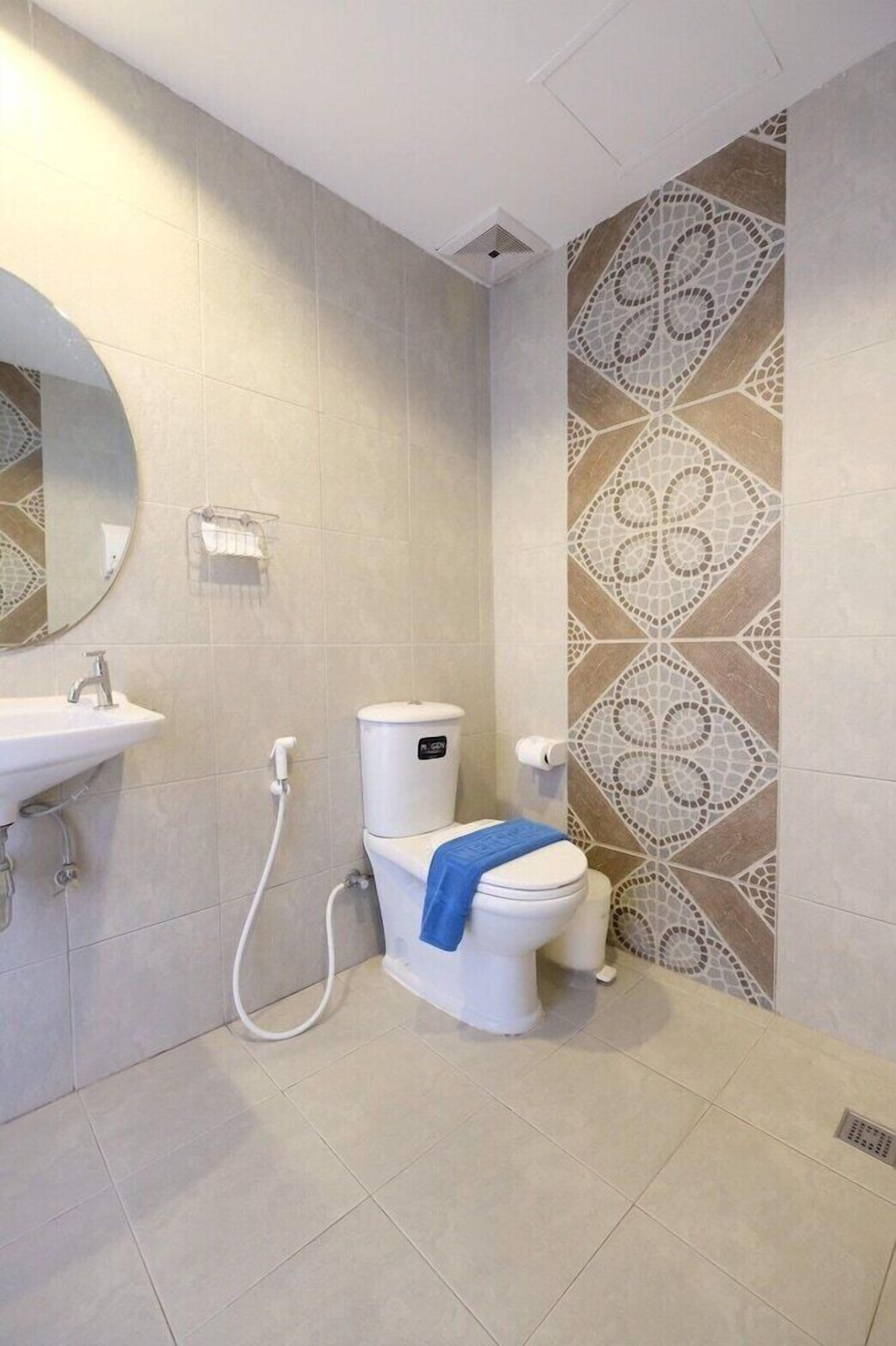 Une salle de bain équipée de toilettes, d’un lavabo et d’un mur décoratif recouvert de carreaux.