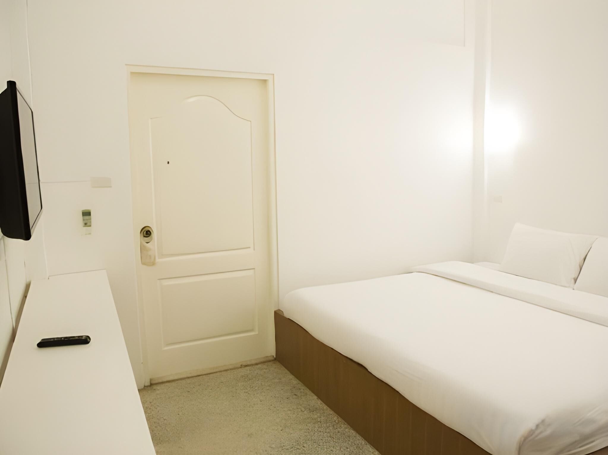 Een kamer met een bed, een bureau en een deur.
