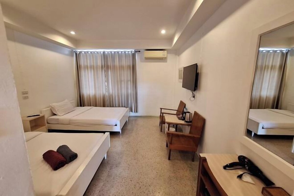 A hotel room with two beds, a desk, a chair, a TV, and a mirror.