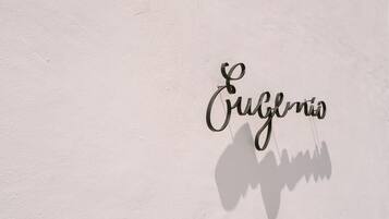 A wall with the word 'Cuneglio' in a cursive font and a shadow of a person.