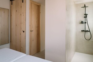 Un dormitorio con cama, armario de madera y zona de ducha con cabezal de ducha manual.