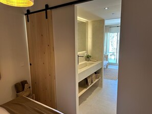 A modern bathroom with a large mirror, a sink, and a potted plant.