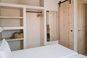 A bedroom with a bed, a wardrobe, and a mirror. - Apartamentos Eugenio by Formentera Passport (Formentera)