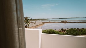 Vista desde un balcón sobre una zona costera con carretera, agua y vegetación.