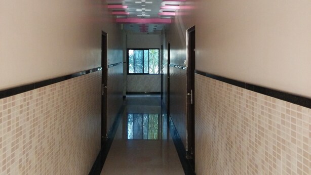 Un pasillo con paredes de baldosas, suelo reflectante y detalles rosados en el techo.