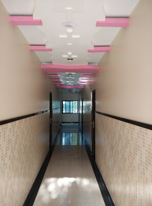 A corridor with tiled walls, a reflective floor, and pink ceiling accents. - Hotel Delta Executive (Rahata)