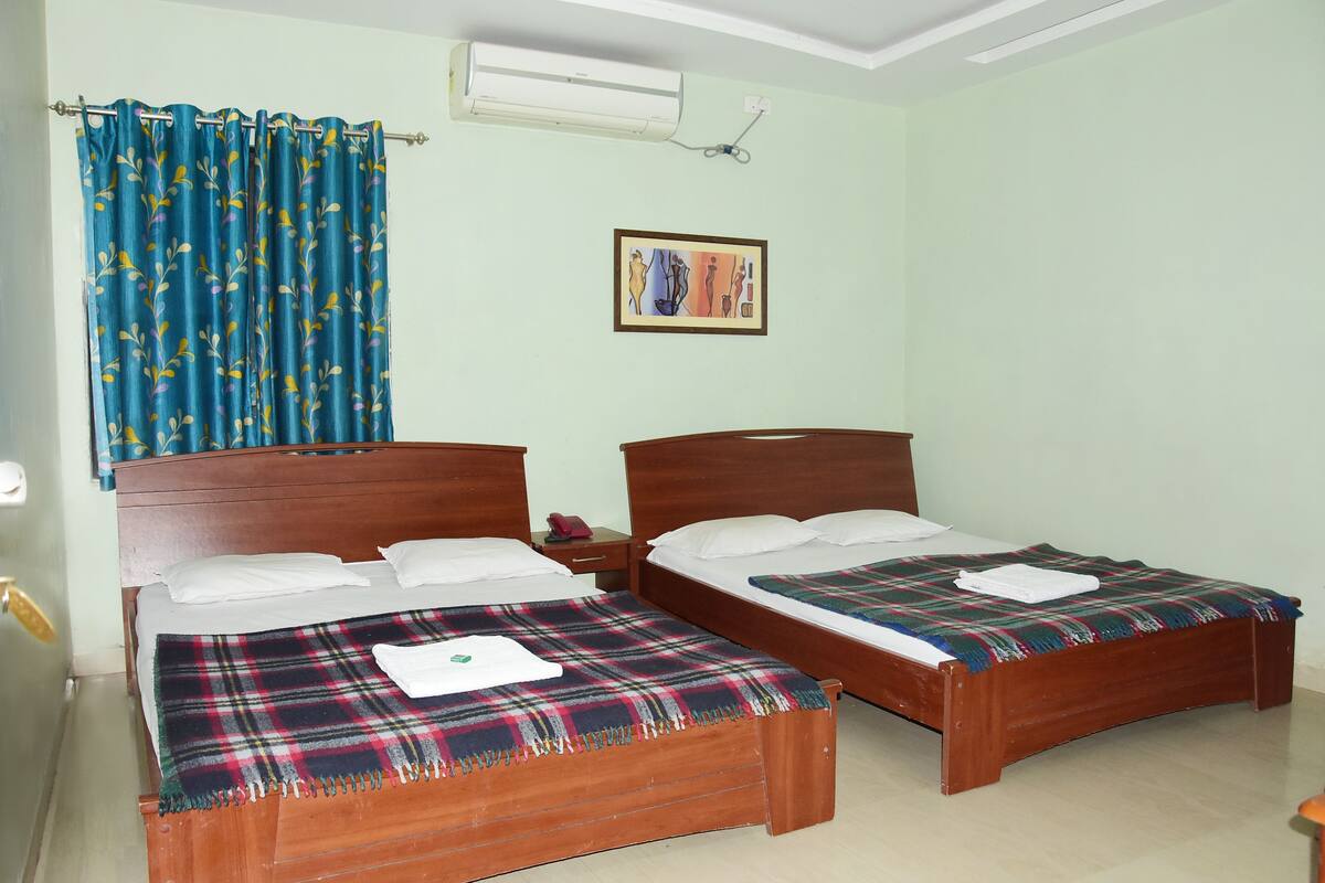 A room with two wooden beds, each with a plaid blanket and white pillows.