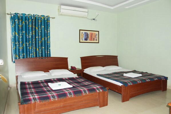 A room with two wooden beds, each with a plaid blanket and white pillows.