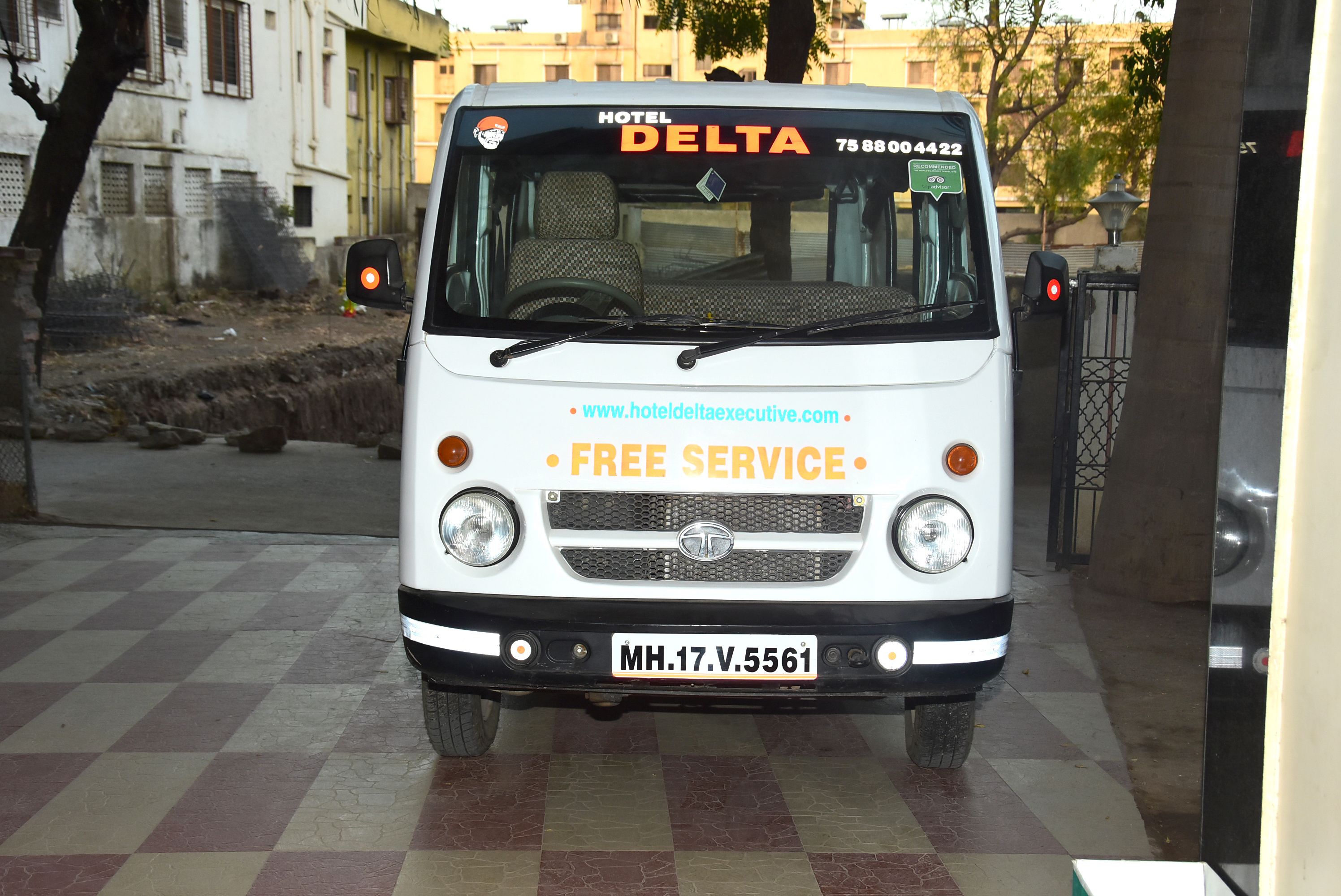 A white vehicle with "HOTEL DELTA" and "FREE SERVICE" text, parked on a checkered pavement.