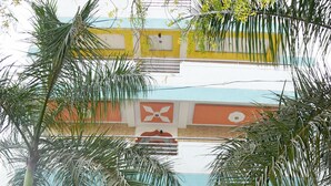 Un edificio con un cartel que indica HOTEL DELTA EXECUTIVE. Un tuk-tuk está estacionado frente a él.
