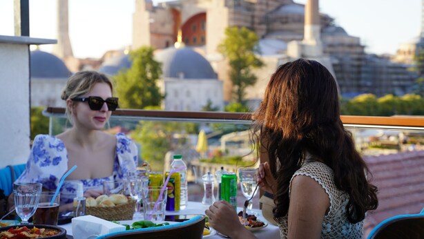 A dining table with food and drinks, a cityscape view, and a building with domes in the background. - Turk Art Hotel (Istanbul)
