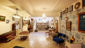 A cozy living room with a fireplace, a blue armchair, and a variety of decorative items on the walls. - Turk Art Hotel (Istanbul)