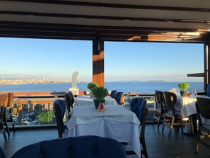A restaurant with a table set for two, overlooking a cityscape and the sea. - Turk Art Hotel (Istanbul)