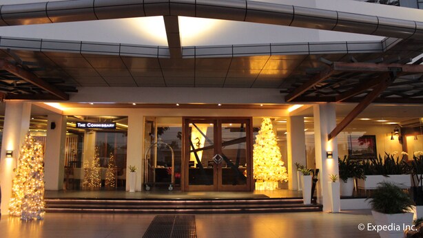 Una entrada de hotel moderna con fachada de vidrio, un árbol de Navidad y un letrero que dice 'The Commissary'.