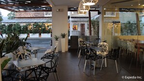 Un café al aire libre con mesas y sillas, una pared de ladrillo y una vista de un edificio al fondo.