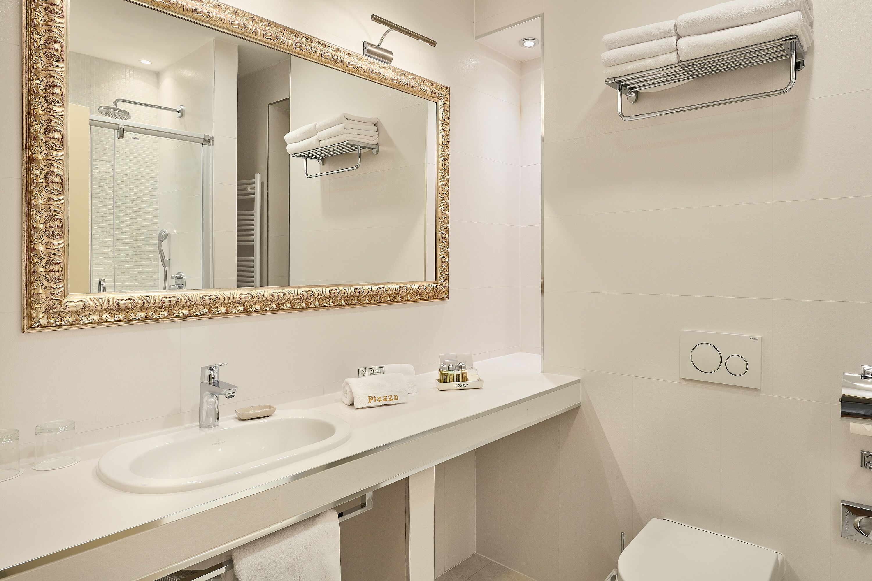 Uma casa de banho moderna com um espelho grande, uma pia, um porta-toalhas e um chuveiro.