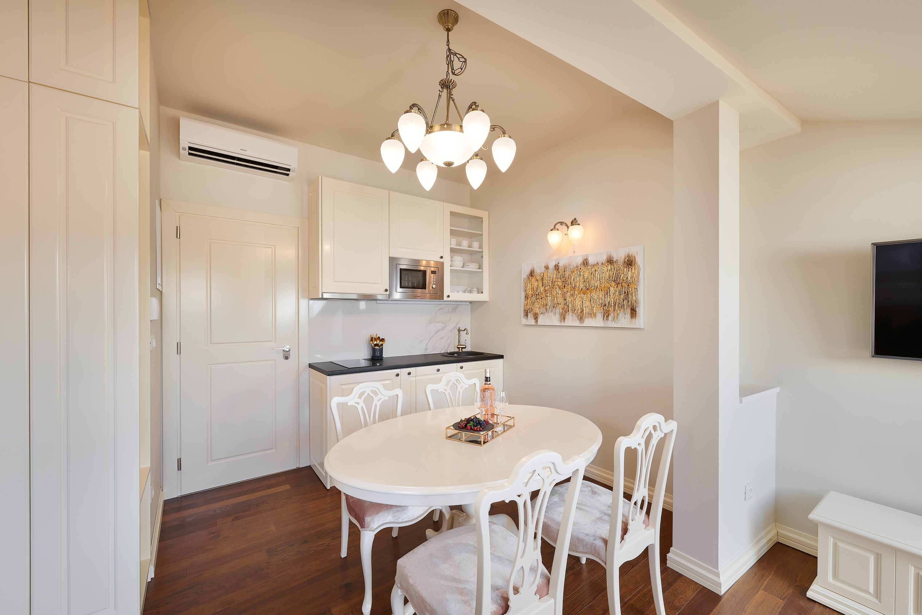 A modern kitchen with white cabinetry, a round dining table, and a chandelier.