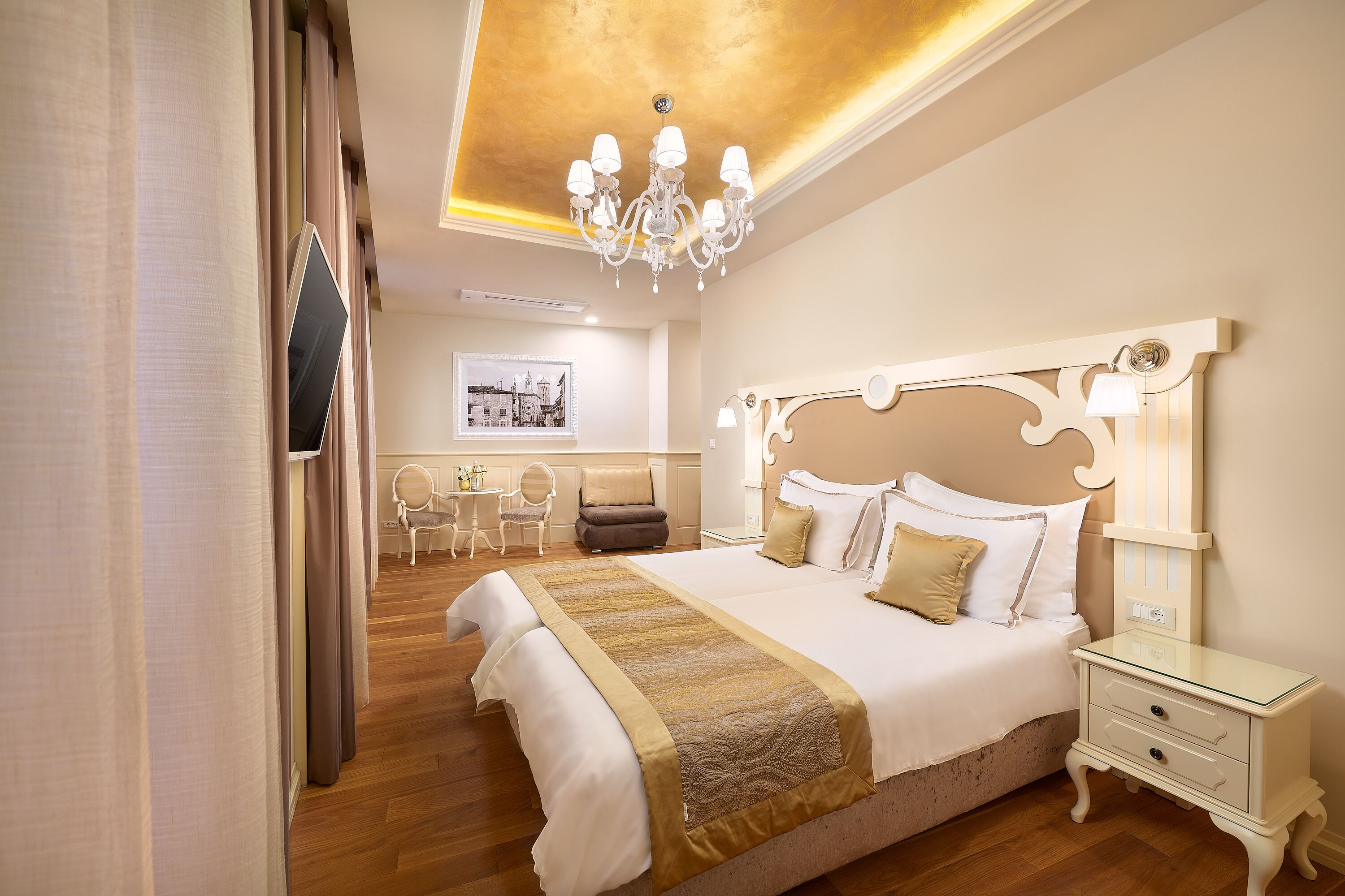 Una camera d'albergo con un letto grande, un comodino, un lampadario e una scrivania con sedie.