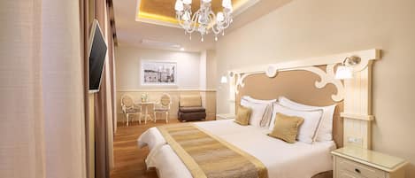 Una camera d'albergo con un letto grande, un comodino, un lampadario e una scrivania con sedie.