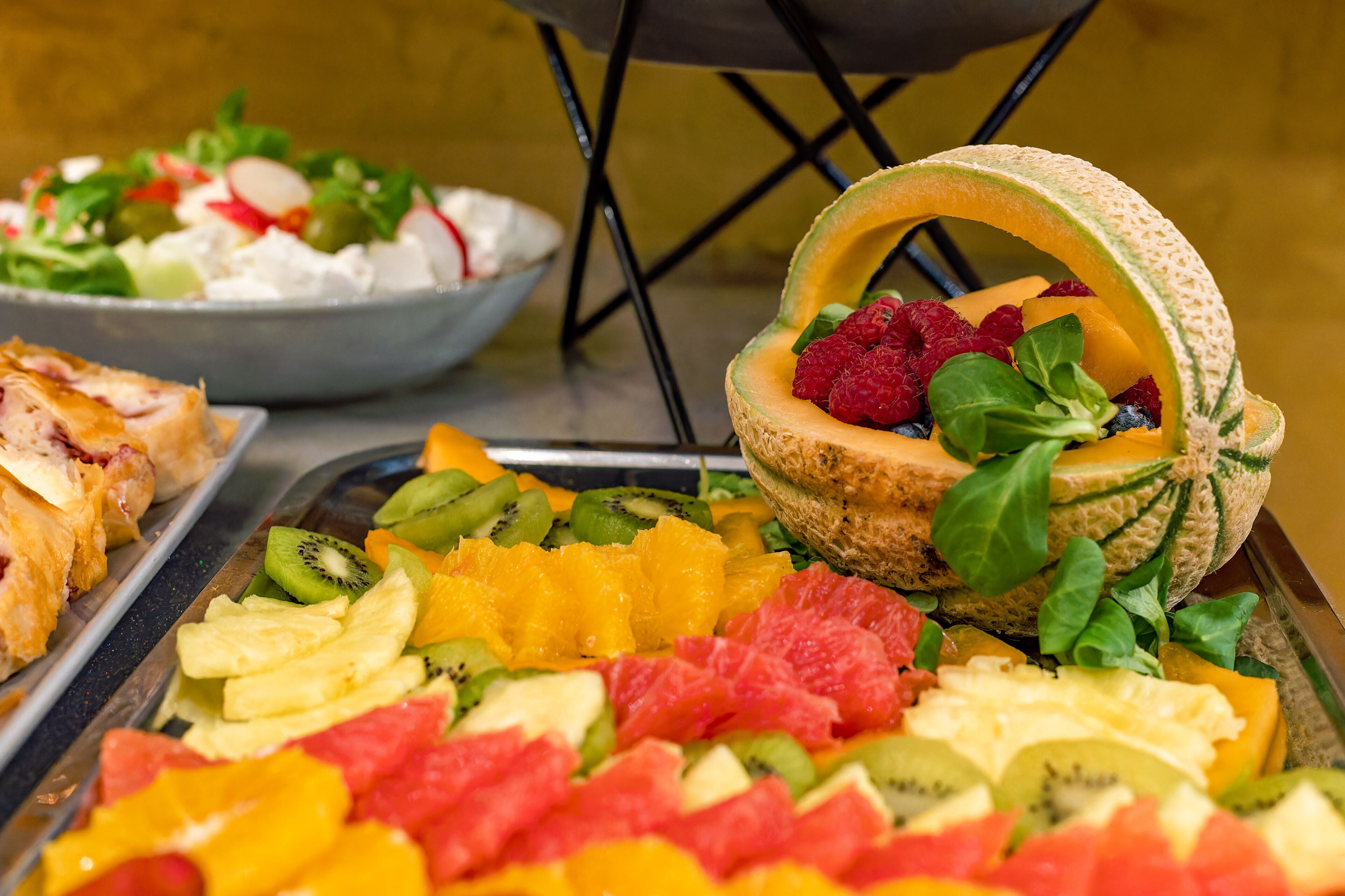 Un bufé con una variedad de frutas y un tazón de ensalada.