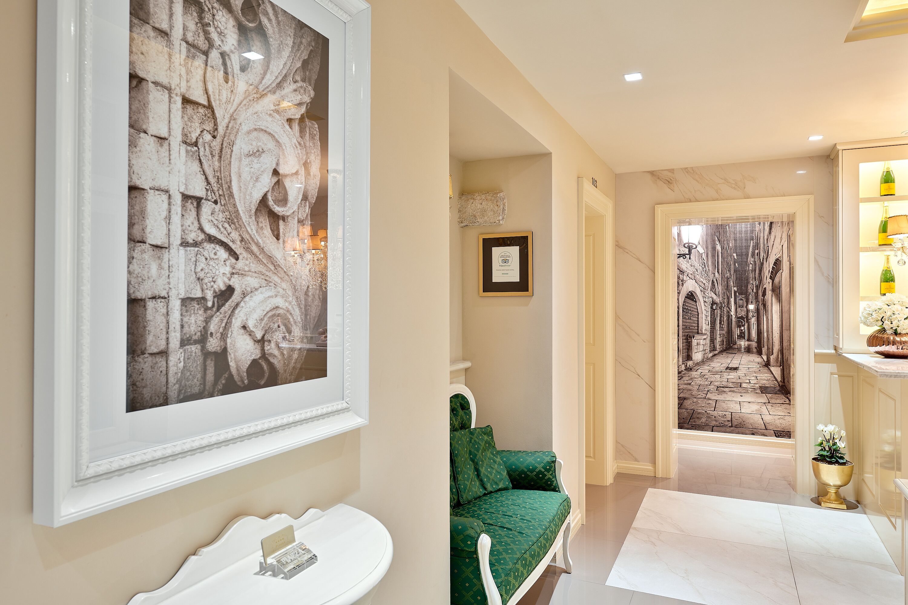 A hallway with a framed artwork, a green sofa, a white sink, and a decorative wall.