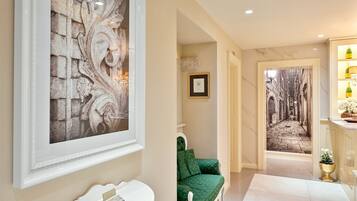 A hallway with a framed artwork, a green sofa, a white sink, and a decorative wall.
