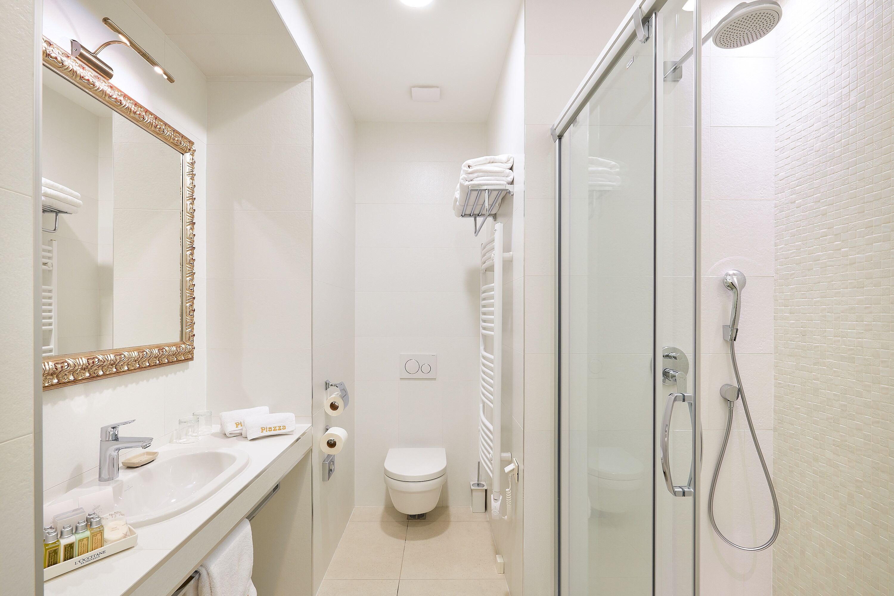 A compact bathroom with a sink, toilet, and shower.