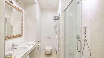 A compact bathroom with a sink, toilet, and shower.