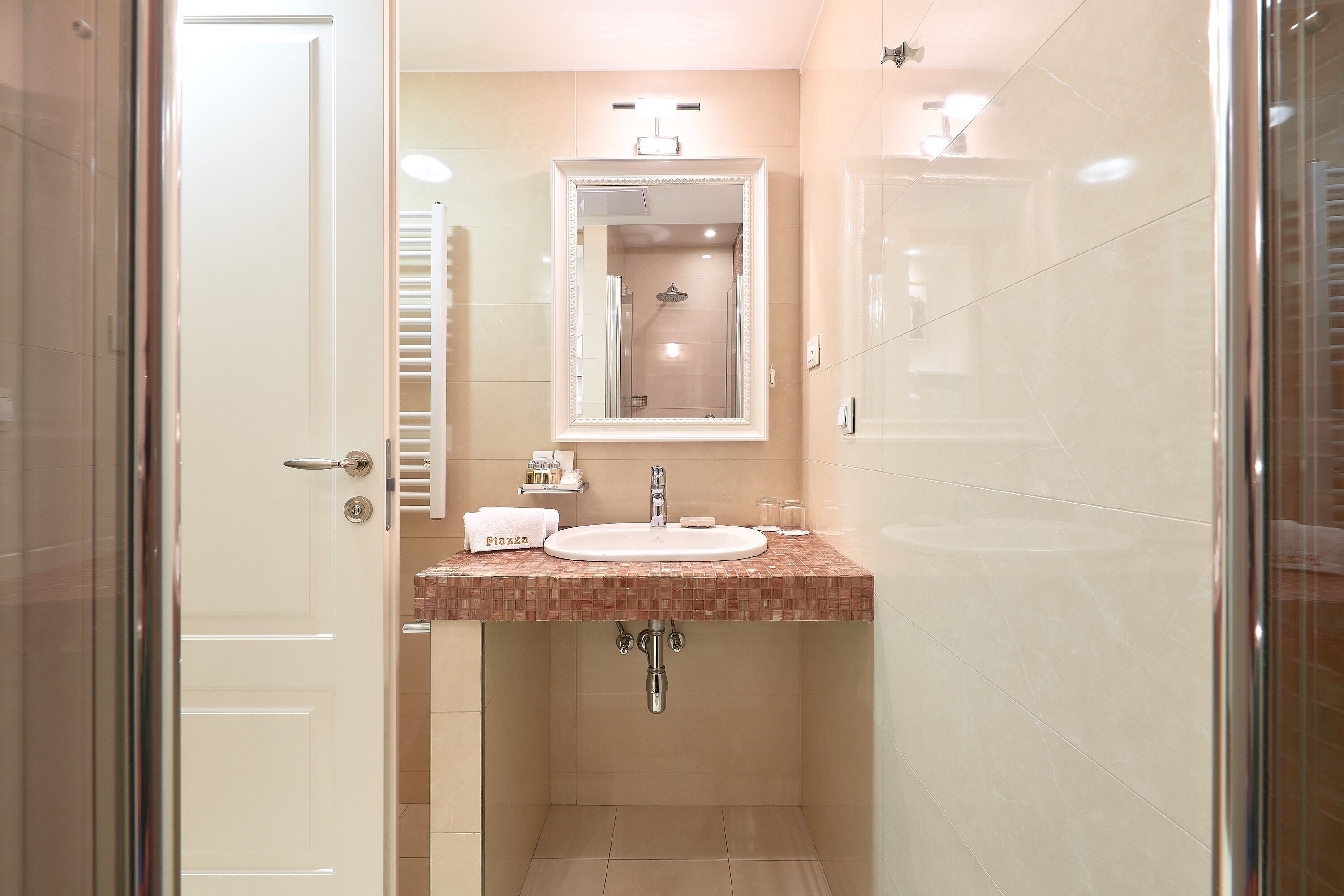 A bathroom with a white sink, a mirror above it, and a shower visible in the background.