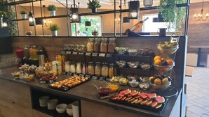 A breakfast buffet with various food items and beverages, including fruits, cereals, and pastries. - Hotel Plaža (Pag)