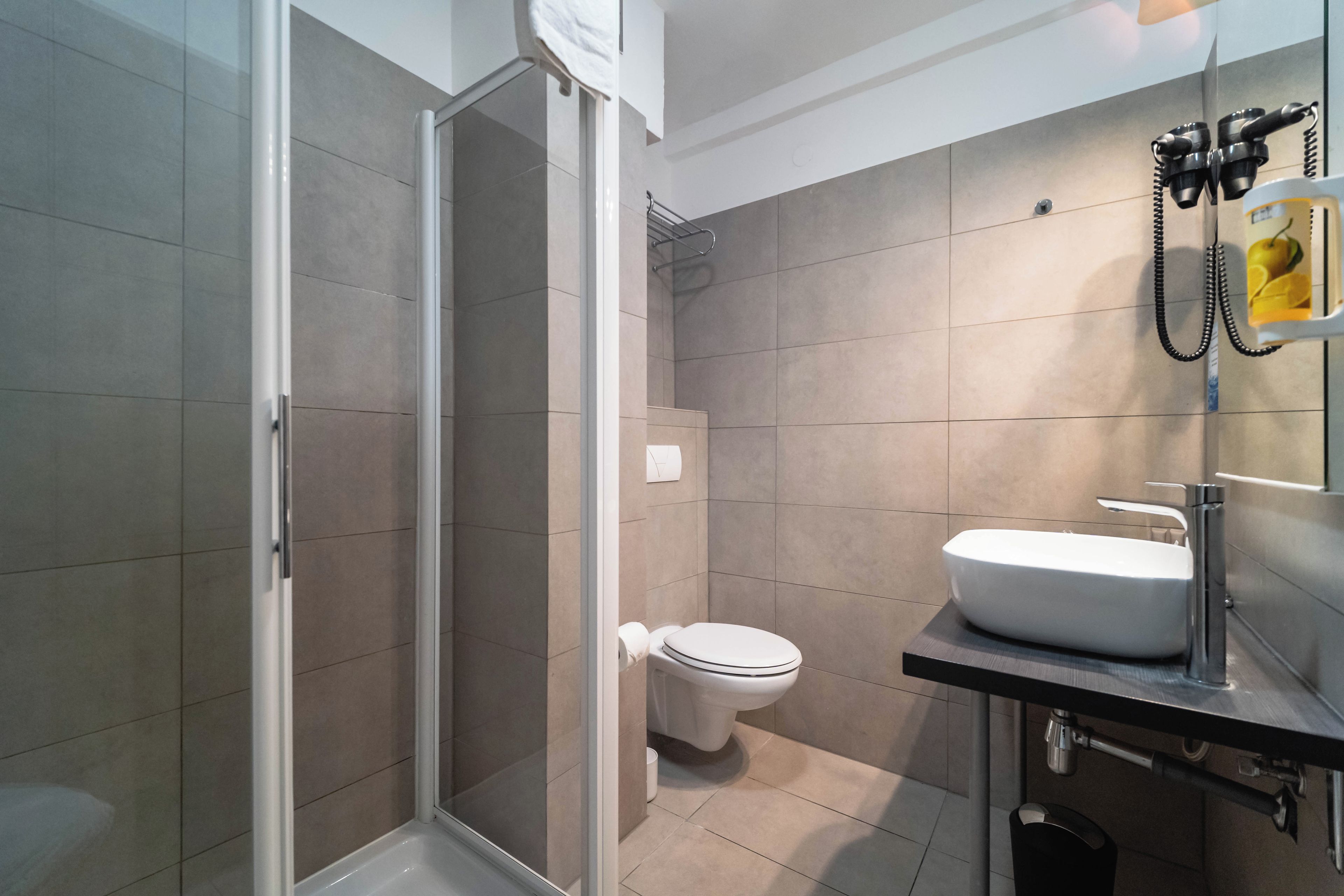 A modern bathroom with a shower, toilet, and sink.
