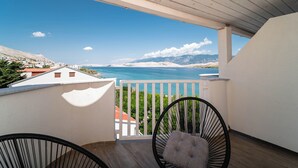 A balcony with a view of the sea and mountains, two chairs, and a white railing. - Hotel Plaža (Pag)