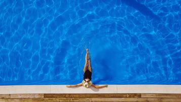 Una piscina al aire libre de temporada, sombrillas, tumbonas